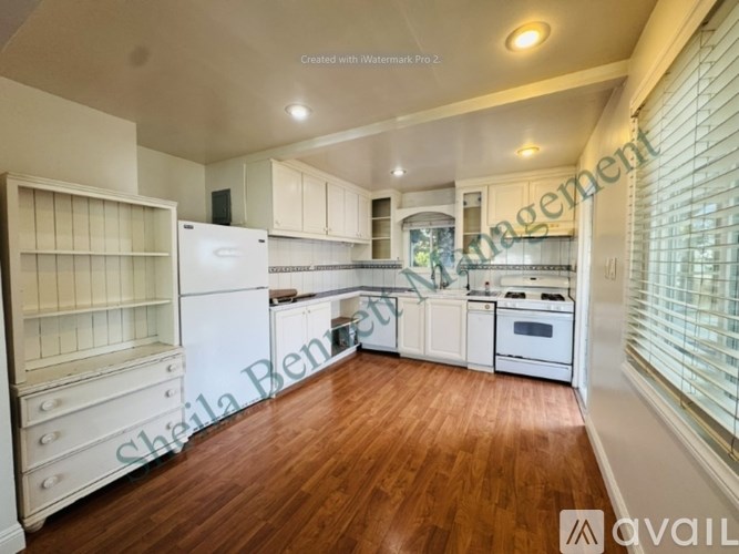 A kitchen with wooden floors and white appliances is available for rent.