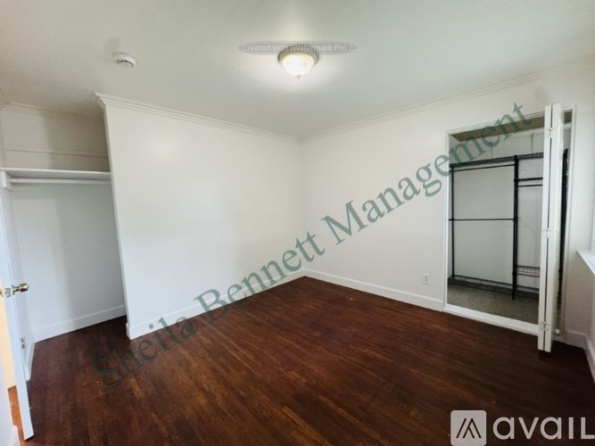 A room with wooden floors and white walls, with a door on the left and a glass door on the right.