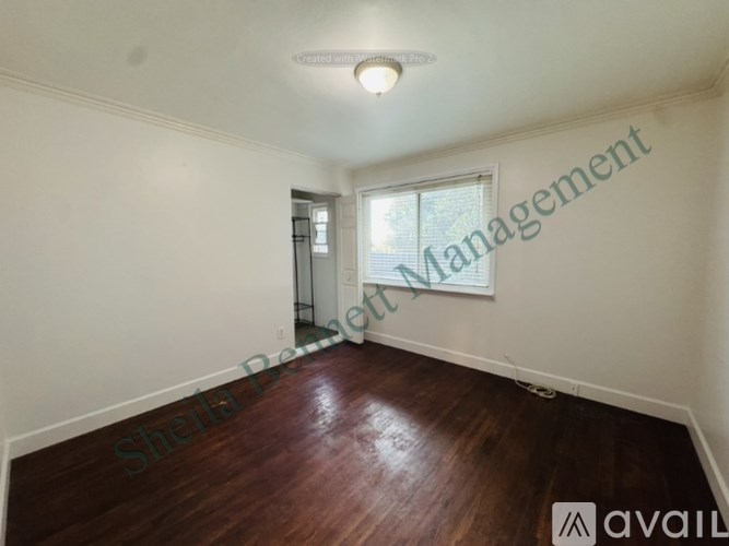 A room with wooden flooring and a window with blinds.
