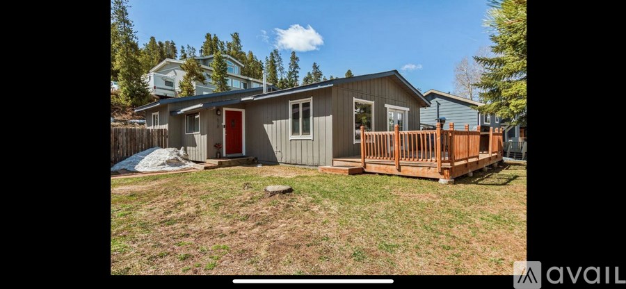 A small house with a red door and a wooden deck.