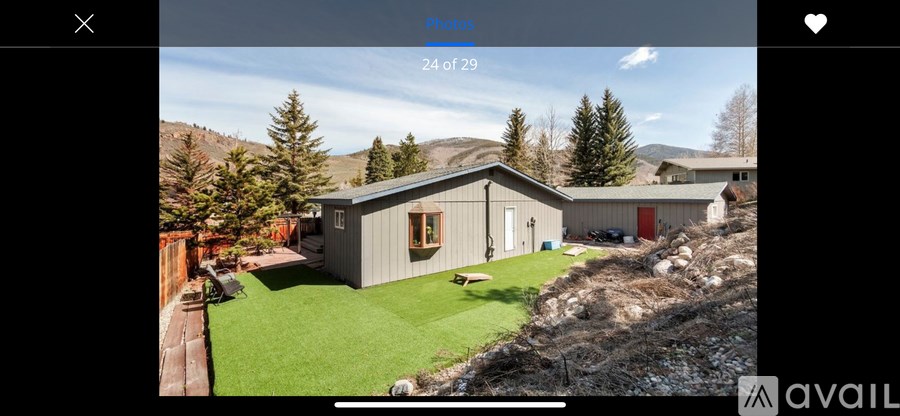A house with a green lawn and a mountain in the background.