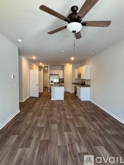 A spacious room with a ceiling fan and wooden flooring.