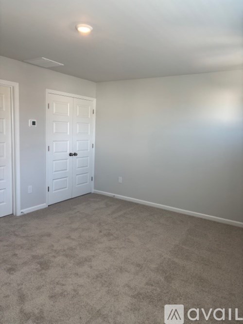 A room with a carpeted floor and a white door.