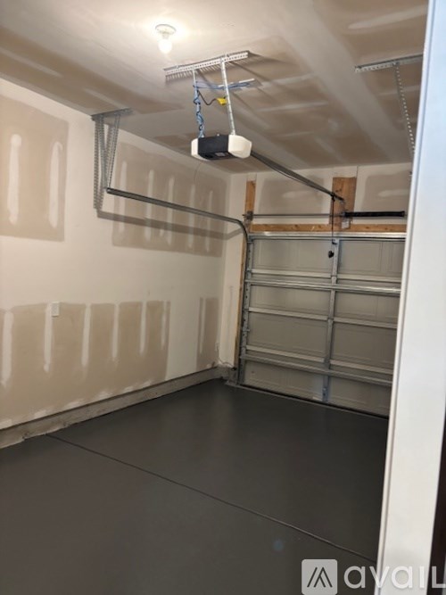 A room with a grey floor and white walls, with a garage door on the right side.