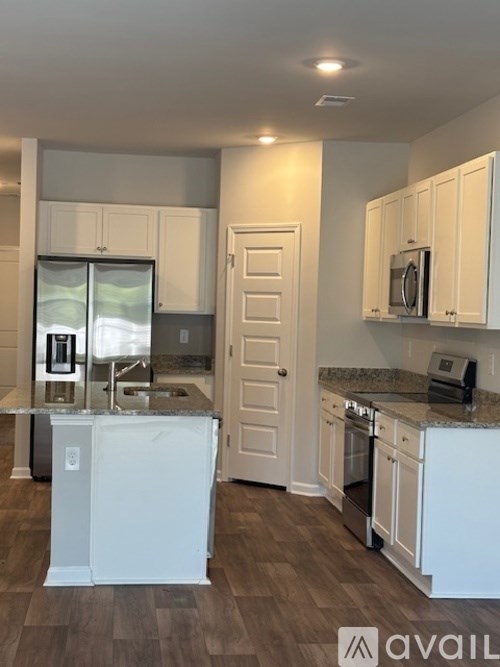 A kitchen with white cabinets and a granite countertop.