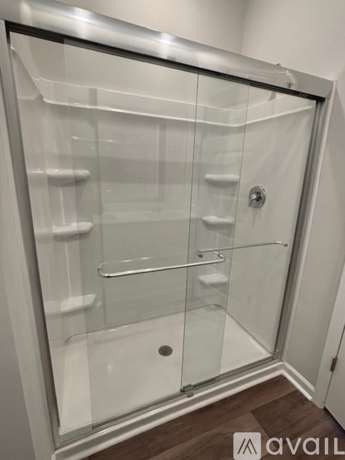 A glass shower door with a handle and a drain.
