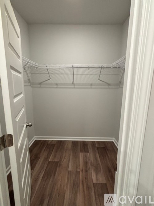 A white closet with a wooden floor and a white door.
