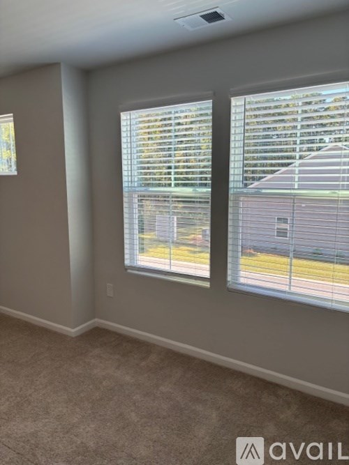 A room with two windows covered in blinds.