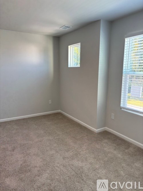 A room with a carpeted floor and a window with blinds.