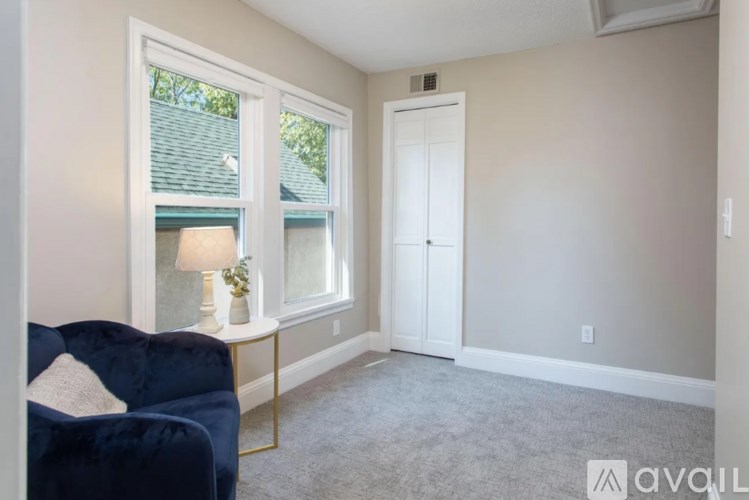 A living room with a blue couch and a lamp on a side table.