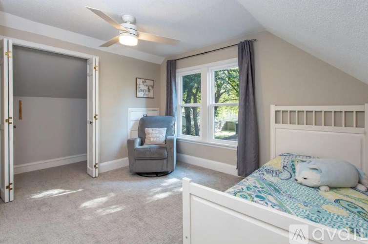 A bedroom with a bed, a chair, and a window.