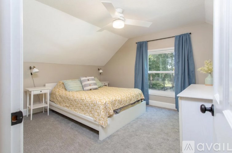 A bedroom with a bed, nightstand, and window.