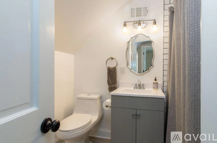 A bathroom with a toilet, sink, and mirror.