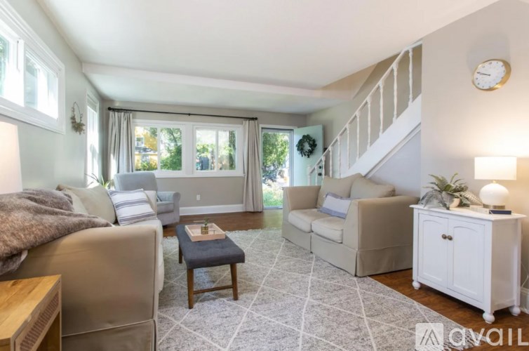 A living room with a couch, a chair, a coffee table, and a staircase.