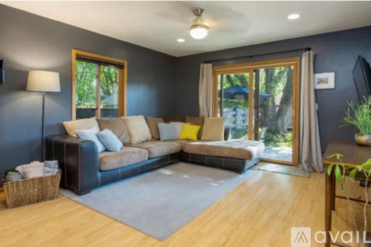 A living room with a grey rug and a black sofa.