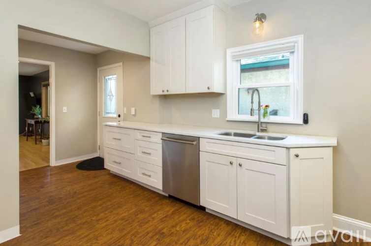 A kitchen with white cabinets and a window above the sink.