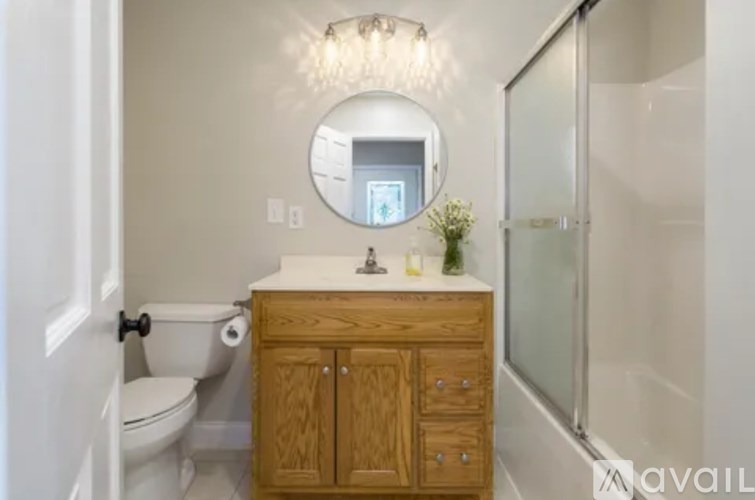 A bathroom with a toilet, sink, and mirror.