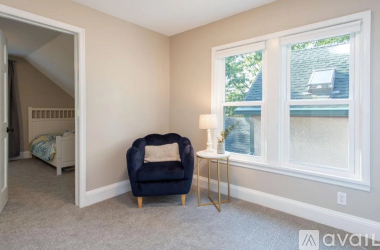A blue chair sits in a corner of a room with a window.