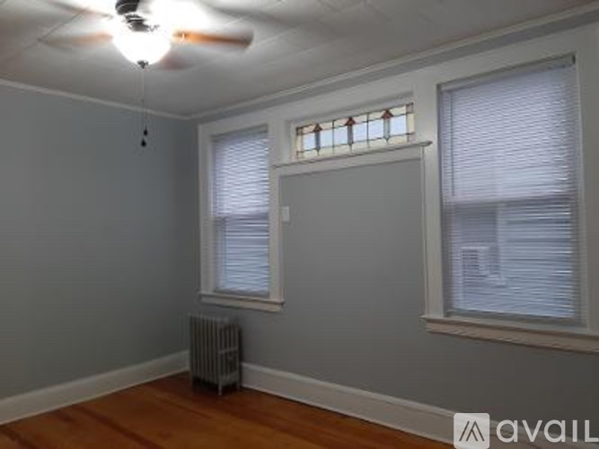 A room with a ceiling fan and two windows.