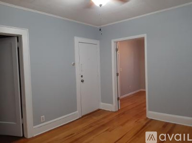 A room with wooden floors and three doors.