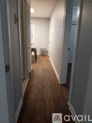 A hallway with a wooden floor and white walls.