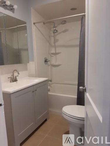 A white toilet sits in a bathroom next to a sink and a shower.