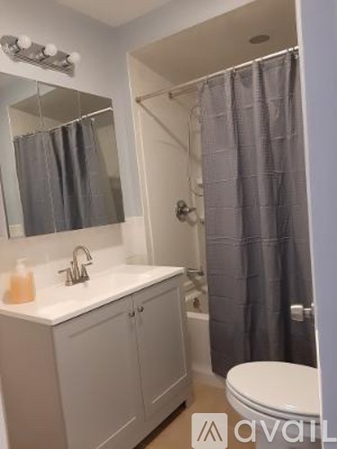 A bathroom with a white counter and grey shower curtain.