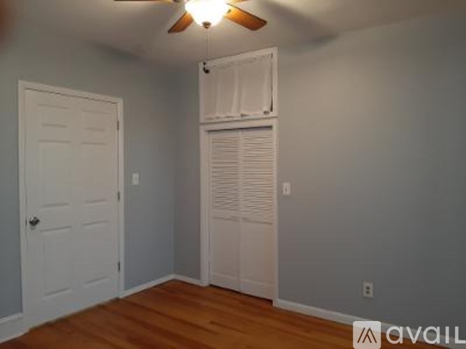 A room with a white door and a white closet with a fan on the ceiling.