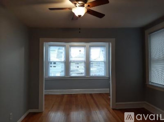 A room with a ceiling fan and a window with blinds.