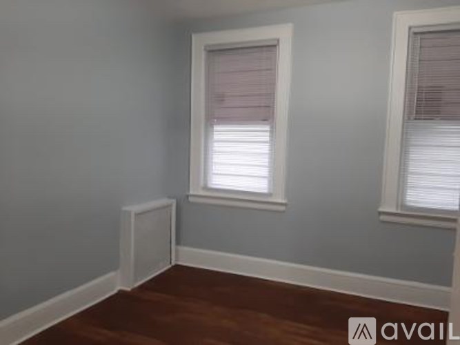 A room with two windows and wooden flooring.
