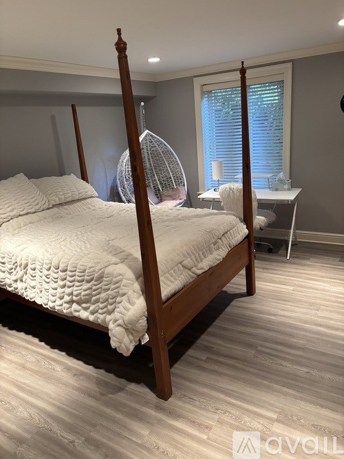 A bedroom with a four poster bed and a desk with a chair.