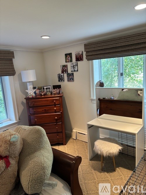 A room with a bed, a chair, a teddy bear and a table.