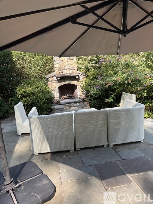 A patio with a white couch and a stone fireplace.