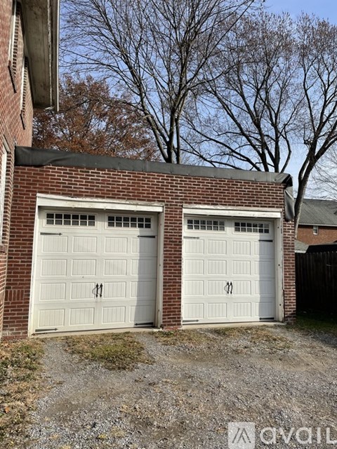 Two white garage doors on a brick building.