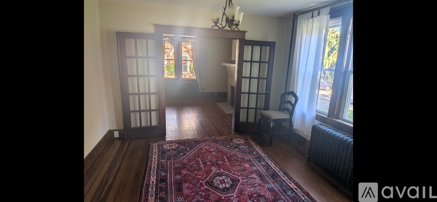 A room with wooden floors and a red rug in the center.