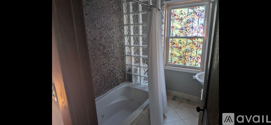 A bathroom with a tub, toilet, and window.
