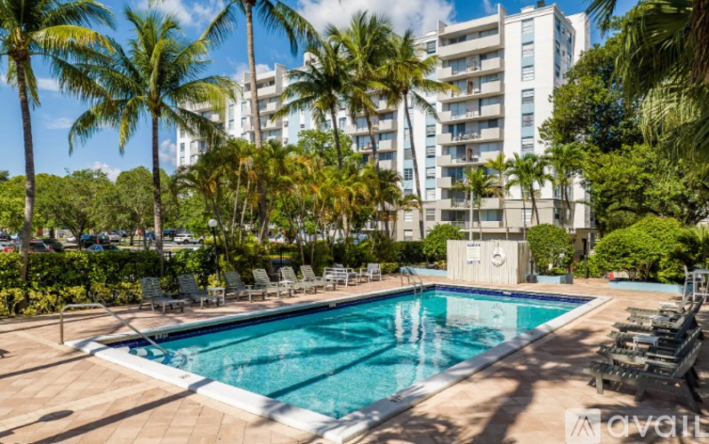 A pool surrounded by palm trees and lounge chairs.