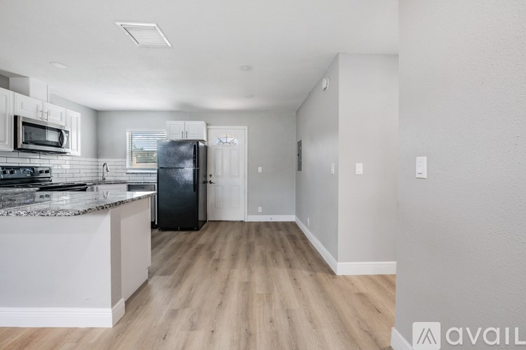A kitchen with a black fridge and wooden floors.