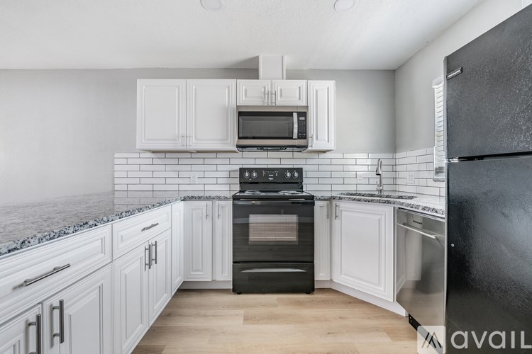 A kitchen with black appliances and white cabinets.