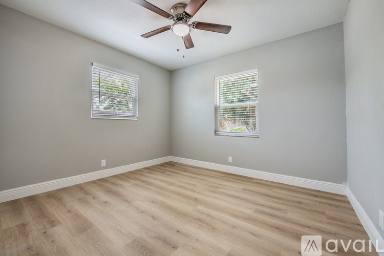 A room with a ceiling fan and two windows.