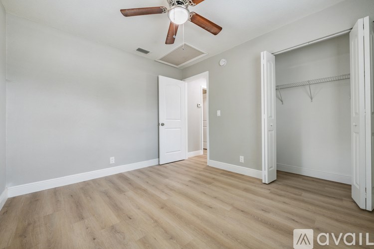 A room with a ceiling fan and wooden flooring.