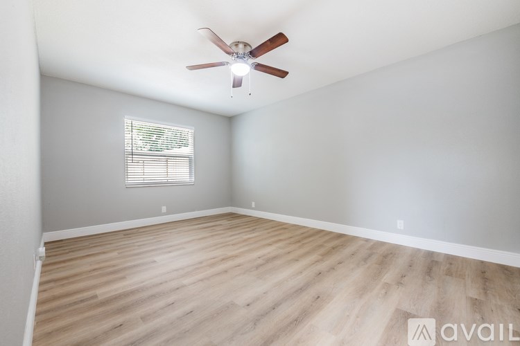 A room with a ceiling fan and wooden flooring.