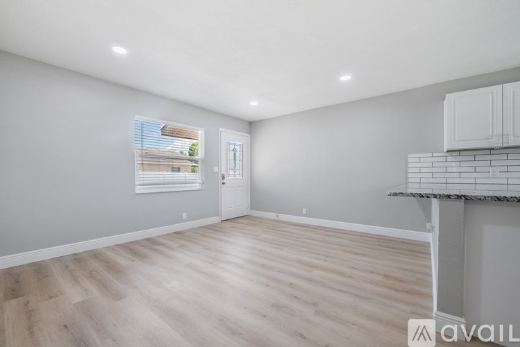 A spacious room with wooden flooring and a window showing a view of a building outside.