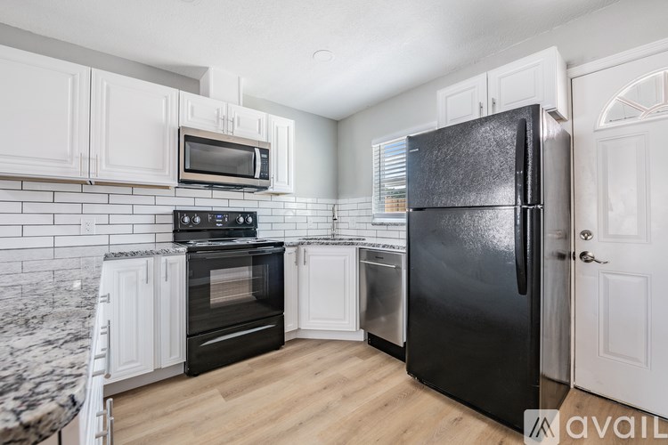 A kitchen with black appliances and white cabinets.