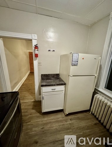A kitchen with a fridge, a stove and a fire extinguisher.