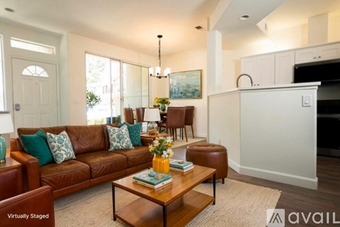 A living room with a brown couch, a coffee table, and a chandelier.