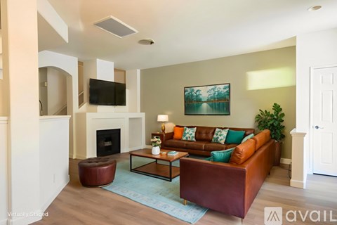 A living room with a brown leather couch and a painting on the wall.