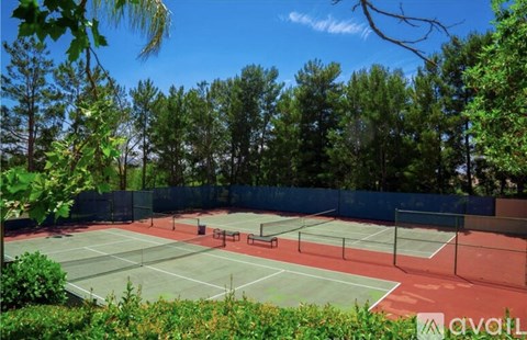 A tennis court surrounded by trees and bushes.