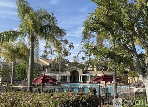 A pool surrounded by trees and a building in the background.