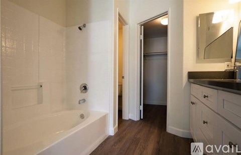 A bathroom with a white tub and wooden floors.